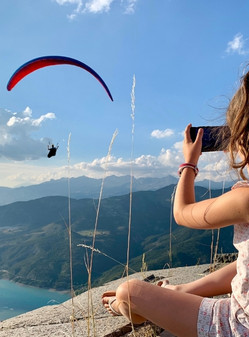 little girl takes picture of paraglider in flight