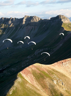 several paragliders in the sky above the mountains